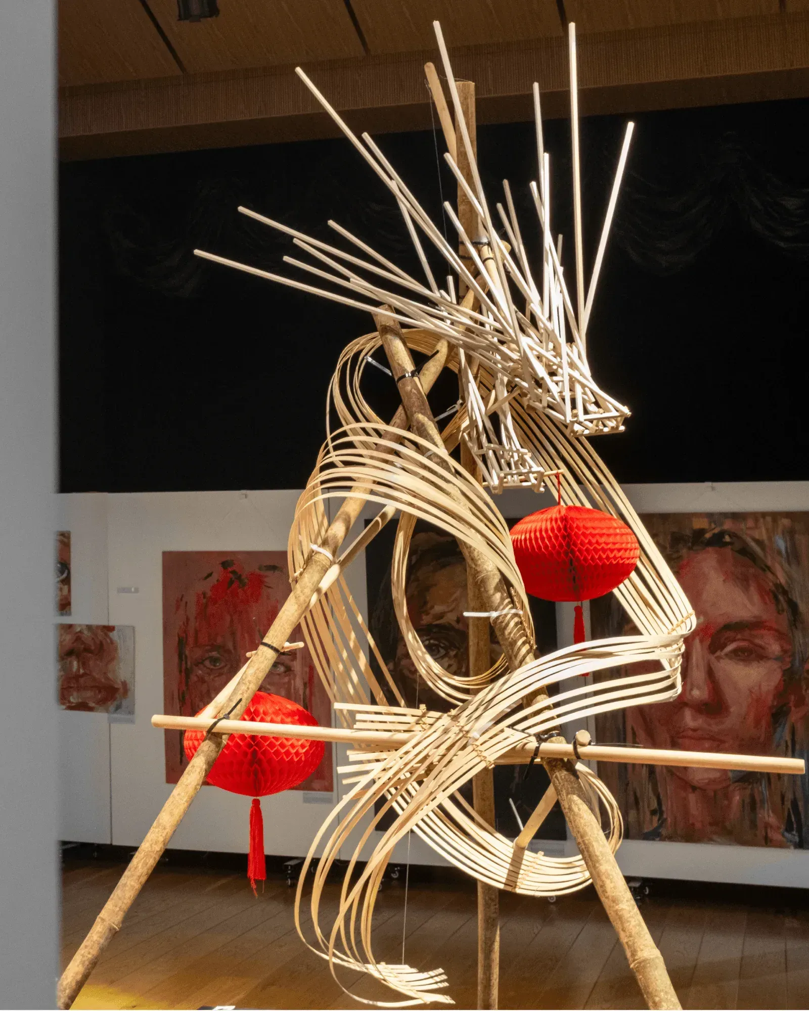 The bamboo dragon's coils around red paper lanterns, painted portraits behind