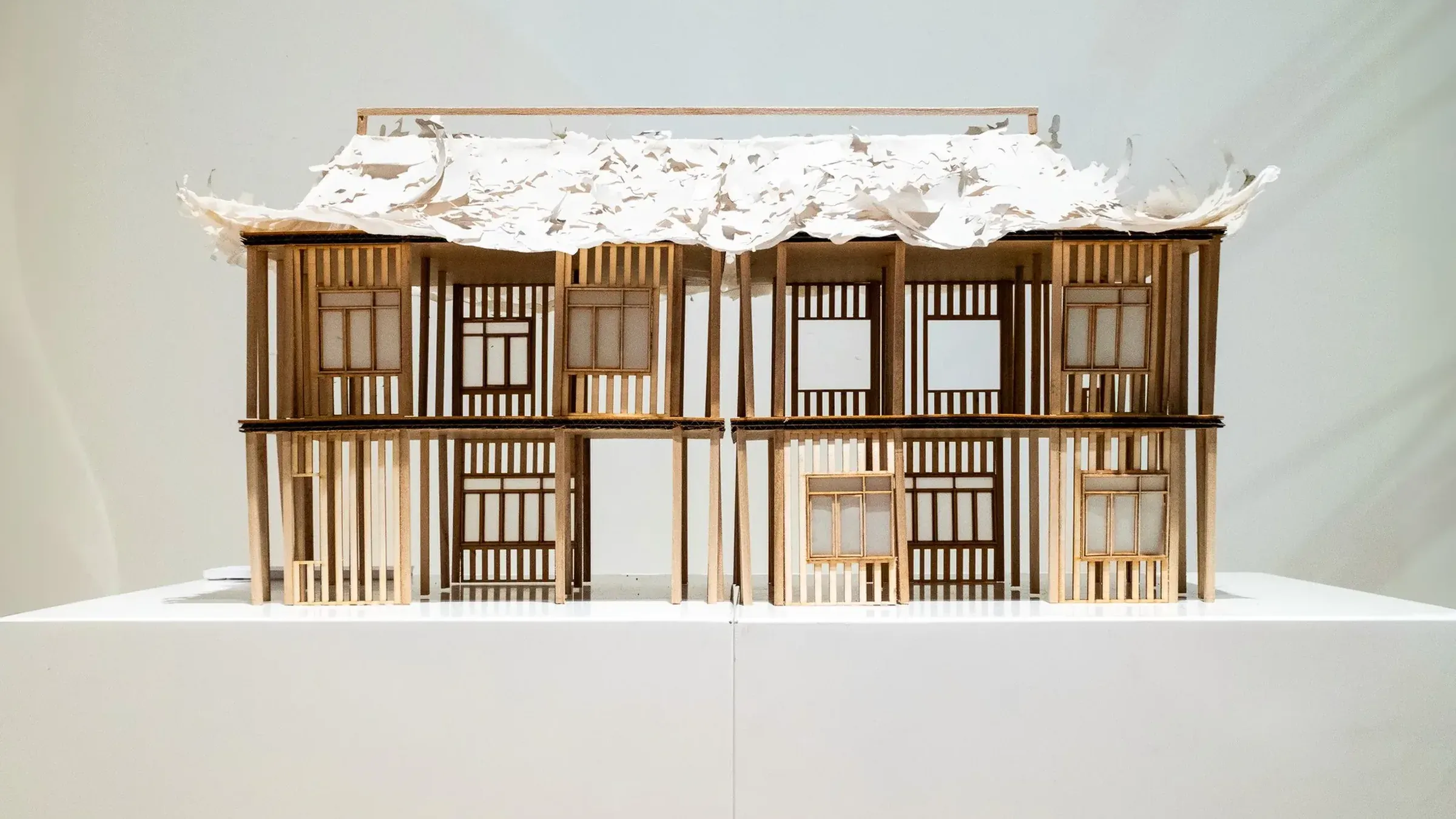 檐下 Under the Eaves, September 2024, balsa, newsprint and crepe paper, 20 × 56 cm: two storeys of shophouse fronts under a torn paper roof